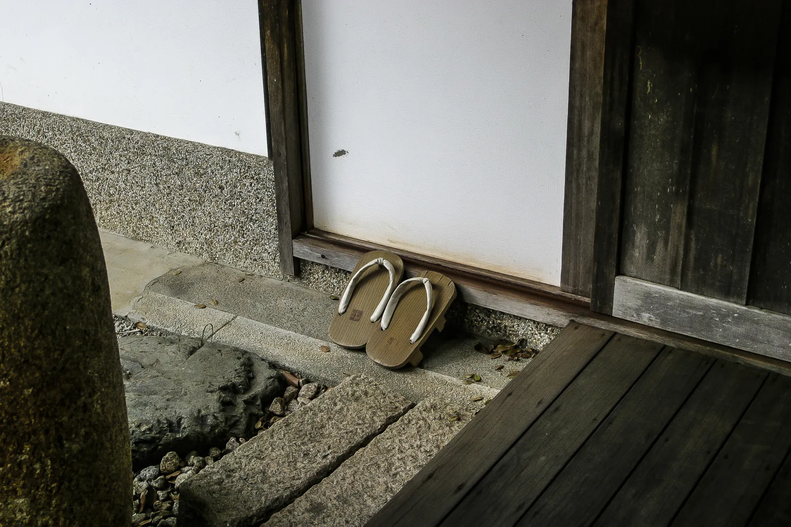 宿の軒先に揃えられた下駄と白壁
